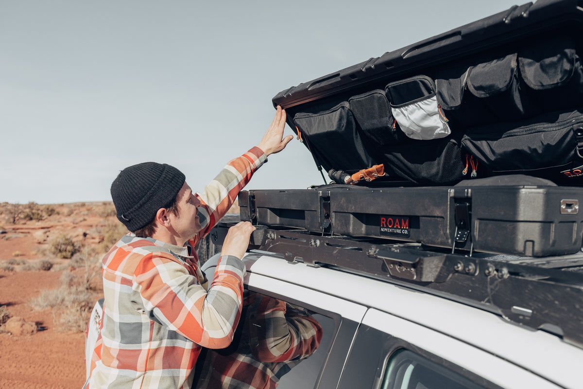 Man using the lid organizer of a low-profile 83L Rugged Case mounted on top of a vehicle enlarged image 5