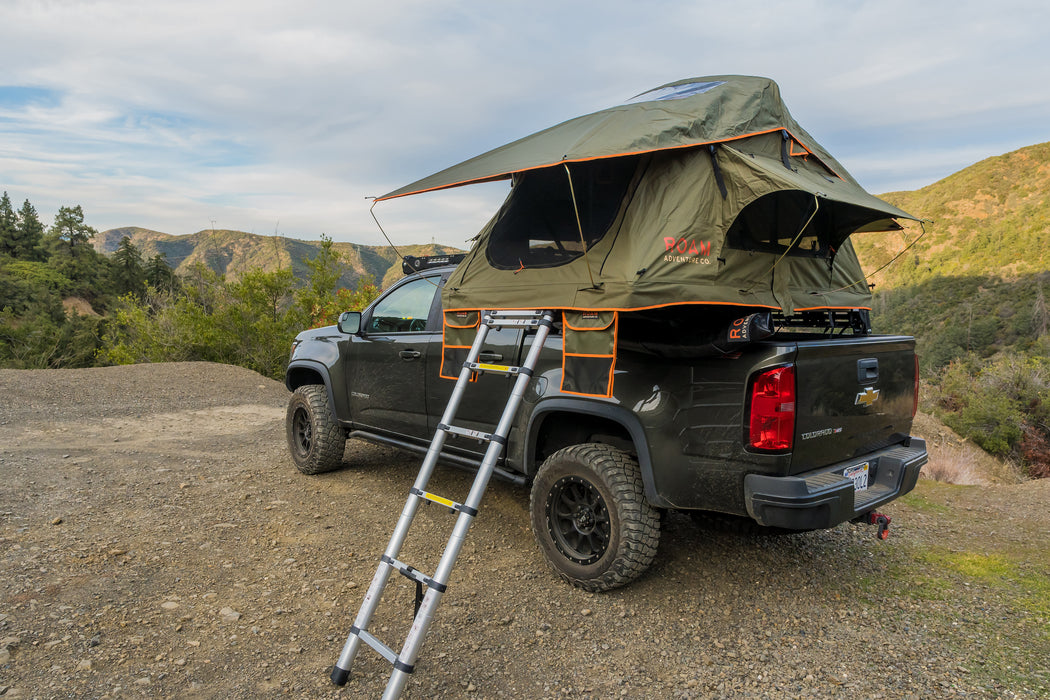 Vagabond Lite Rooftop Tent in Forest Green Hyper Orange with telescopic ladder shown on a truck